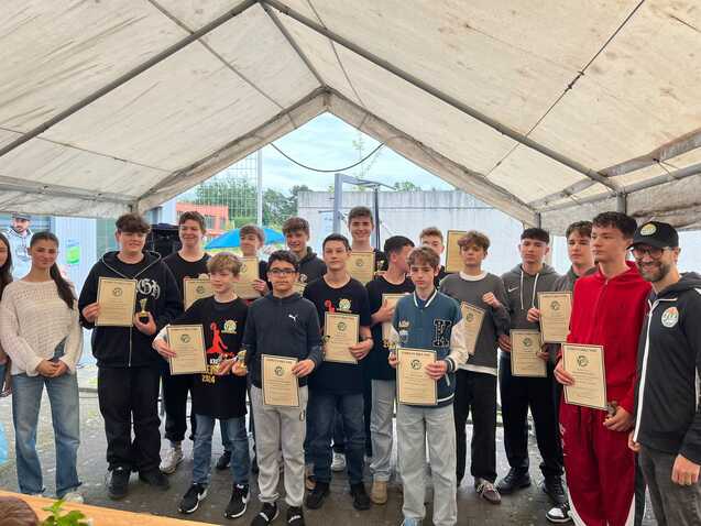 Gruppe von Jugendlichen mit Urkunden unter einem Zelt, lächelnd, während sie an einem Wettkampf teilnehmen.