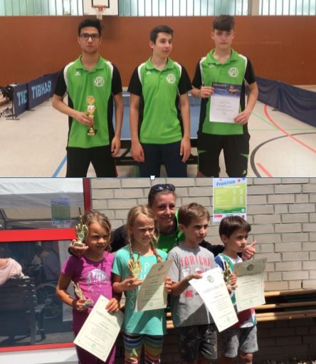 Zwei Gruppen von Kindern und Jugendlichen mit Pokalen und Urkunden nach einem Tischtennisturnier in einer Sporthalle.