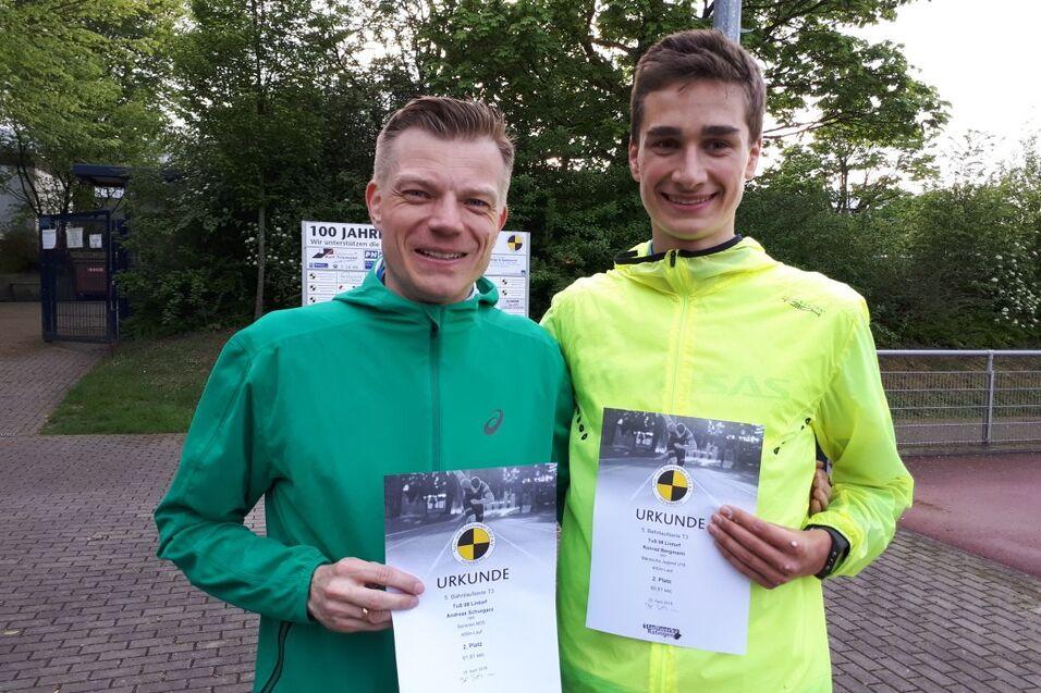 Zwei M&auml;nner halten Urkunden in der Hand, stehen im Freien vor einer gr&uuml;nen Landschaft und l&auml;cheln in die Kamera.