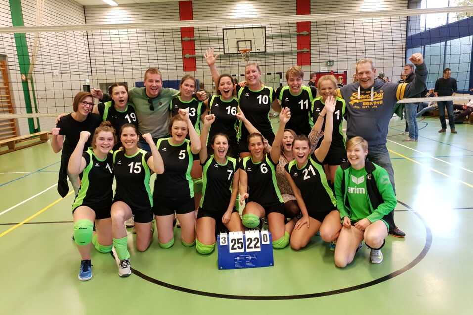 Gruppe von Volleyballspielern in gr&uuml;n-schwarzen Trikots feiert einen Sieg vor dem Netz, Punktestand 25:22.