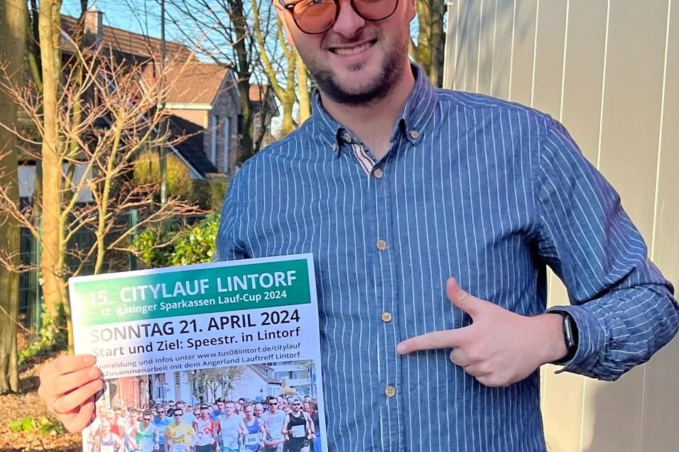 Mann mit Brille h&auml;lt ein Plakat zum 15. Citylauf Lintorf am 21. April 2024 in der Hand. Hintergrund mit B&auml;umen.