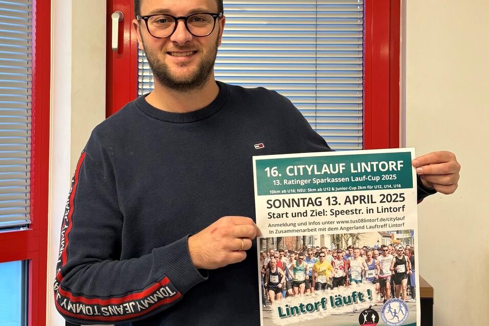 Mann h&auml;lt ein Plakat des 16. Citylauf Lintorf mit Details zum Event in einer B&uuml;roumgebung.
