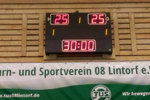 Ergebnisanzeige mit 25:25 Punkten und einer Uhrzeit von 30:00 Minuten in einer Sporthalle. Banner des Vereins im Hintergrund.