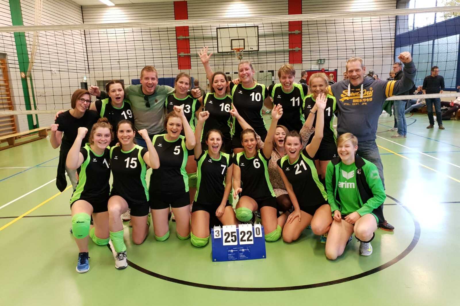 Gruppe von Volleyballspielern in gr&uuml;n-schwarzen Trikots feiert einen Sieg vor dem Netz, Punktestand 25:22.