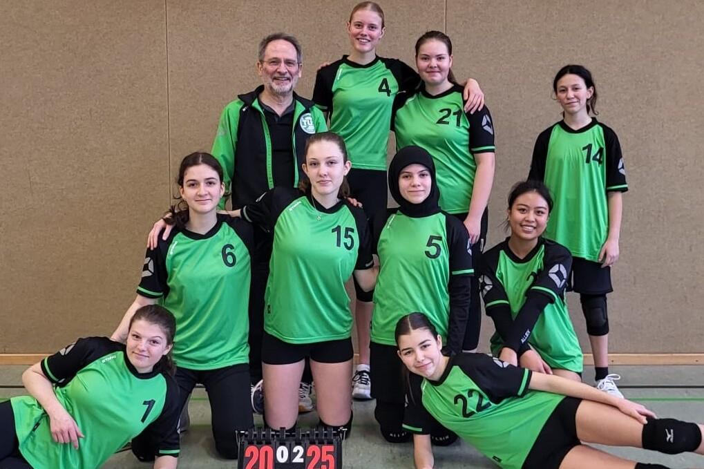 Mannschaftsfoto von neun vollem Mädchen in grünen Sporttrikots, stehend und kniend, mit einem Punktestand von 20:25.