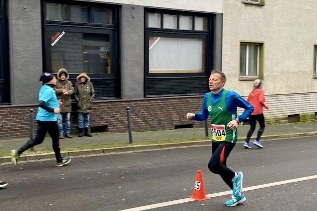 Ein Läufer mit Nummer 504 rennt auf einer Straße, während Zuschauer im Hintergrund stehen.