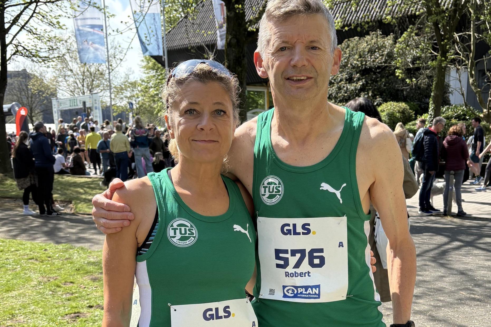 Zwei Läufer stehen lächelnd nebeneinander, gekleidet in grüne Trikots mit den Startnummern 575 und 576.