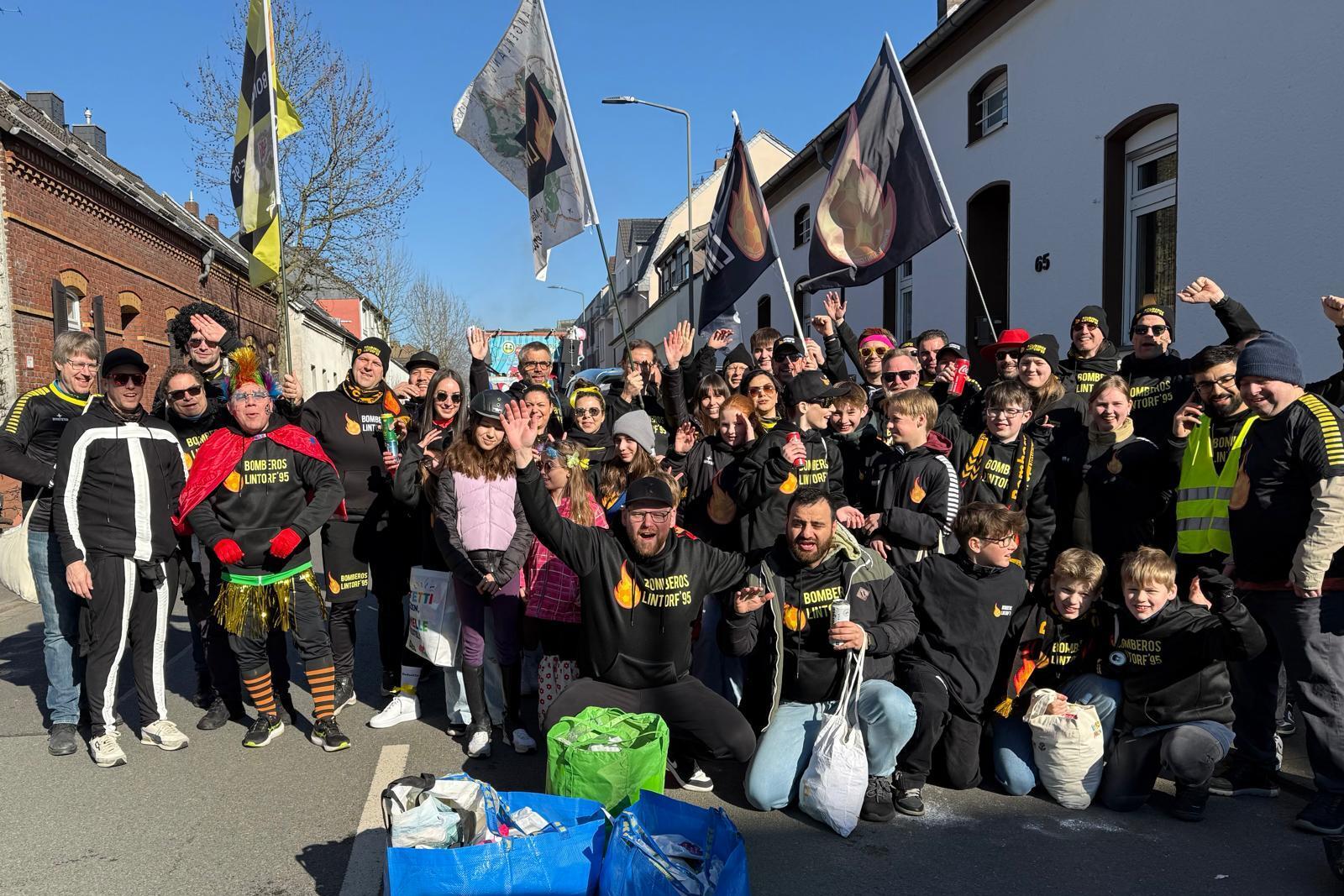 Gruppe von Menschen in Festkleidung, die auf einer Straße stehen und fröhlich posieren, mit Flaggen im Hintergrund.