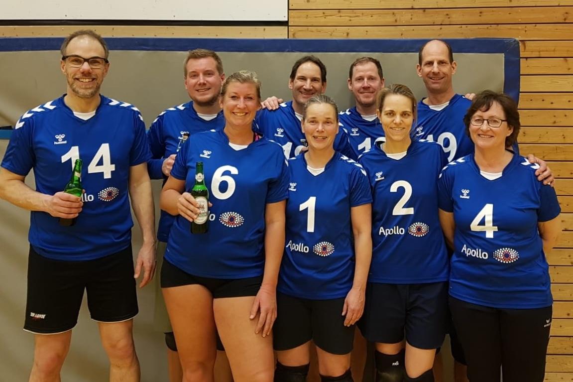 Gruppe von zehn Volleyballspielern in blauen Trikots, posierend in einer Sporthalle.