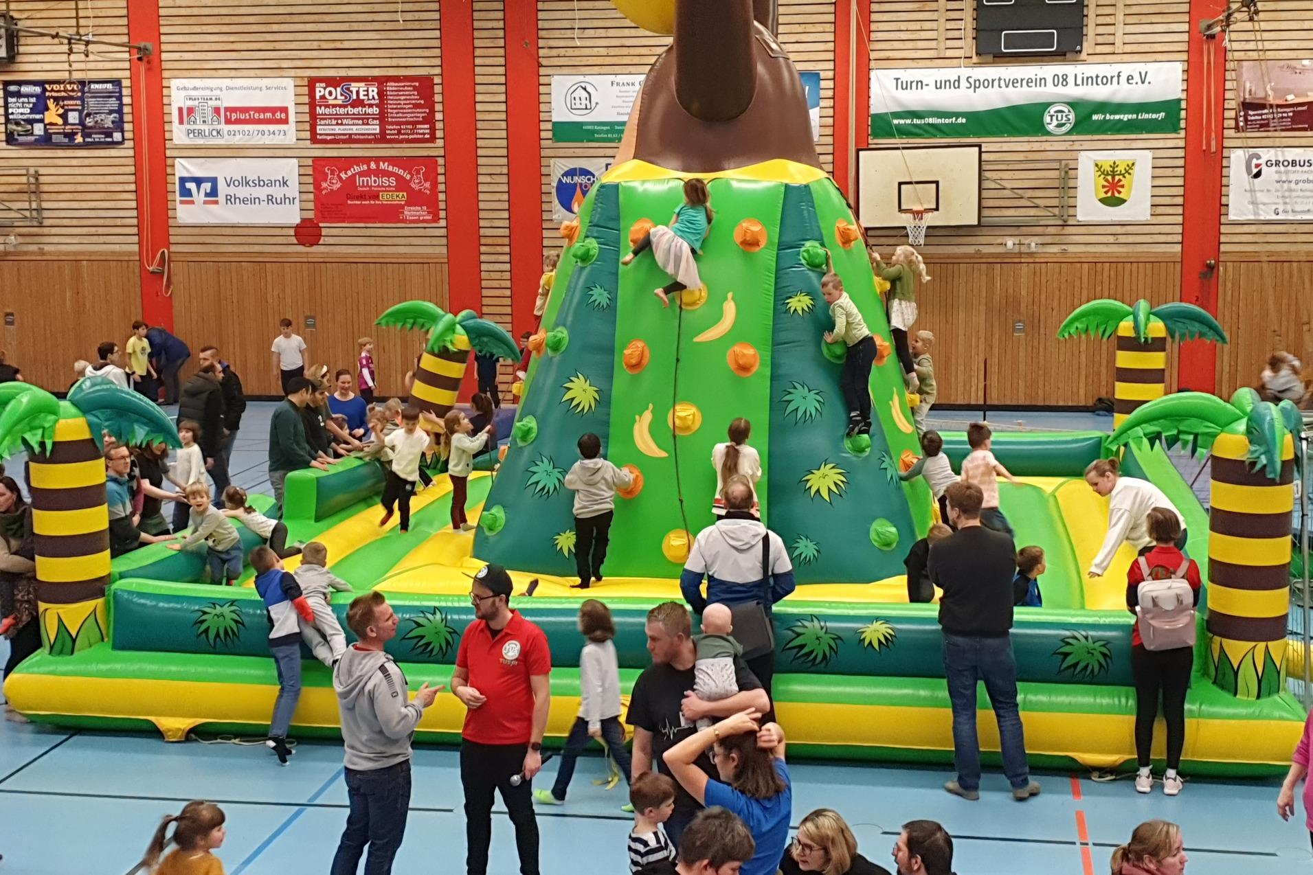 Kinderspielplatz mit Piratenthema: Bunte Hüpfburg mit Kletterwand und zahlreichen Kindern in einer Veranstaltungshalle.