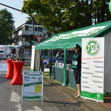 Messestand mit einem Zelt, Pr&auml;sentationen f&uuml;r Sportarten und einem Mitarbeiter des TuS, im Hintergrund ein Stra&szlig;enverkehr.