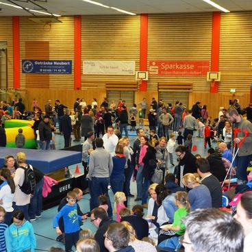 Vollbesetzte Sporthalle mit zahlreichen Familien und Kindern, verschiedenen Spielger&auml;ten und bunten H&uuml;pfburgen.