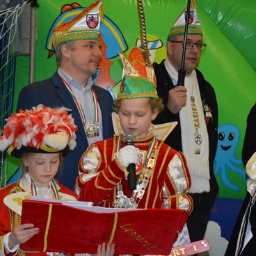 Gruppe von Karnevalisten in traditionellen Kost&uuml;men auf einer B&uuml;hne, w&auml;hrend sie auf eine Feier vorbereitet sind.