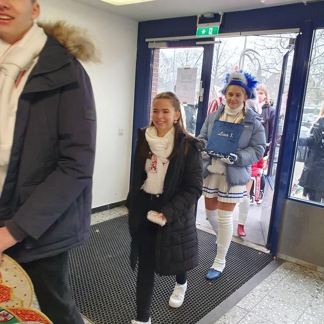 Gruppenausgang von Jugendlichen in Winterkleidung, eine Person tr&auml;gt ein Kost&uuml;m mit blauem Hut und wei&szlig;en Str&uuml;mpfen.