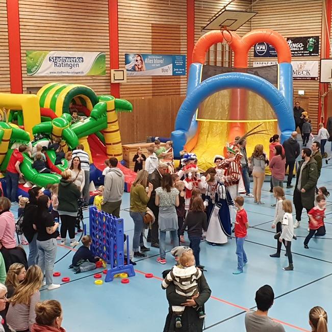 Volles Gemeindezentrum mit Kindern und Erwachsenen, die auf Luftburg und Spielger&auml;ten spielen. Bunte Attraktionen &uuml;berall.