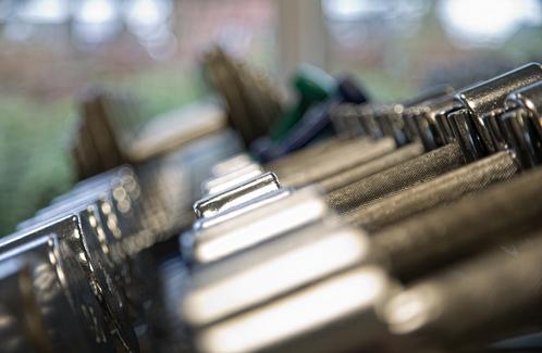 Nahaufnahme einer Reihe von Metallgewichten in einem Fitnessstudio mit unscharfem Hintergrund.