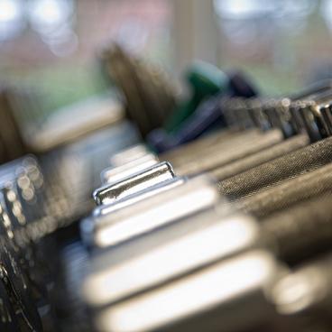 Nahaufnahme einer Reihe von Metallgewichten in einem Fitnessstudio mit unscharfem Hintergrund.