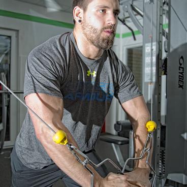Mann in Sportkleidung f&uuml;hrt eine Zug&uuml;bung an einem Kabelzugger&auml;t im Fitnessstudio aus.