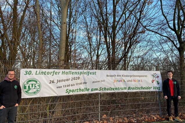Zwei M&auml;nner stehen neben einem gro&szlig;en Banner f&uuml;r das 30. Lintorfer Hallenspiel fest 26. Januar 2020, am Sportzentrum.