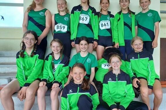 Gruppe von zehn M&auml;dchen in Sportkleidung, die sich auf einer Treppe f&uuml;r ein Gruppenfoto aufstellen.