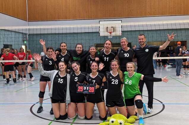 Volleyballmannschaft mit 11 Spielerinnen und Trainer feiert den Sieg, mit einem Punktestand von 25:20 auf dem Spielbrett.