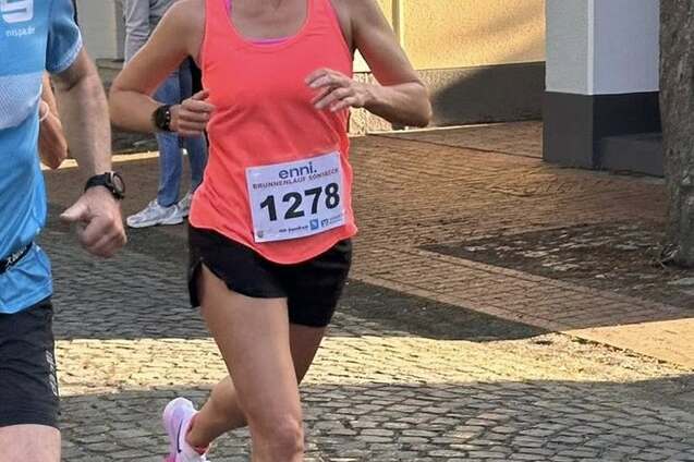 Frau in pinkem Sporttop l&auml;uft auf einem Kopfsteinpflasterweg, w&auml;hrend ein Mann neben ihr l&auml;uft. Teilnehmernummer 1278 sichtbar.