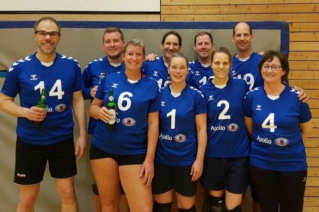 Gruppe von zehn Volleyballspielern in blauen Trikots, posierend in einer Sporthalle.