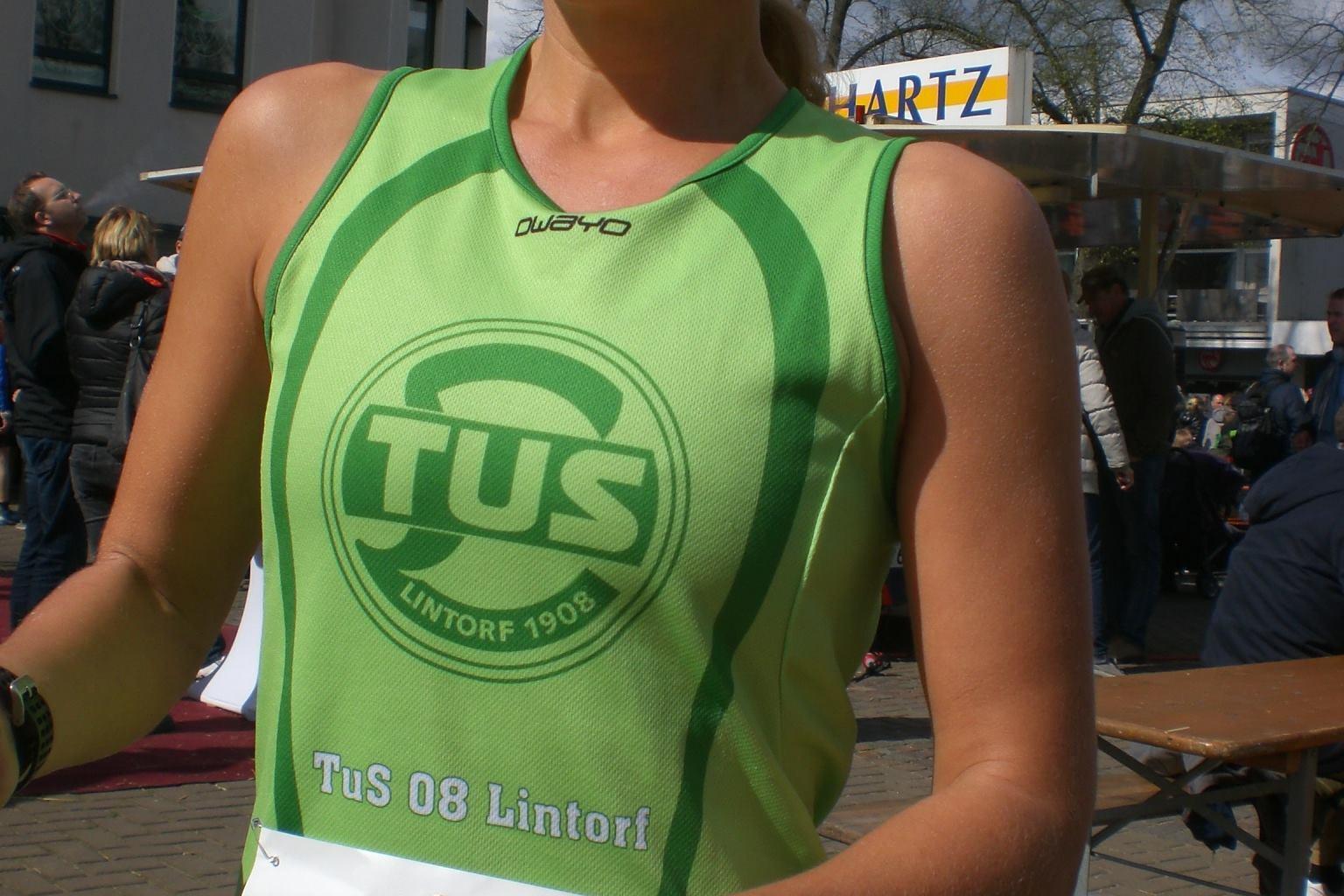 L&auml;uferin tr&auml;gt ein gr&uuml;nes Trikot mit dem Schriftzug &bdquo;TuS 08 Lintorf&ldquo; und h&auml;lt eine Startnummer in der Hand.