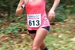 L&auml;uferin in pinkem Shirt mit der Nummer 613 joggt auf einem Waldweg zwischen buntem Herbstlaub.