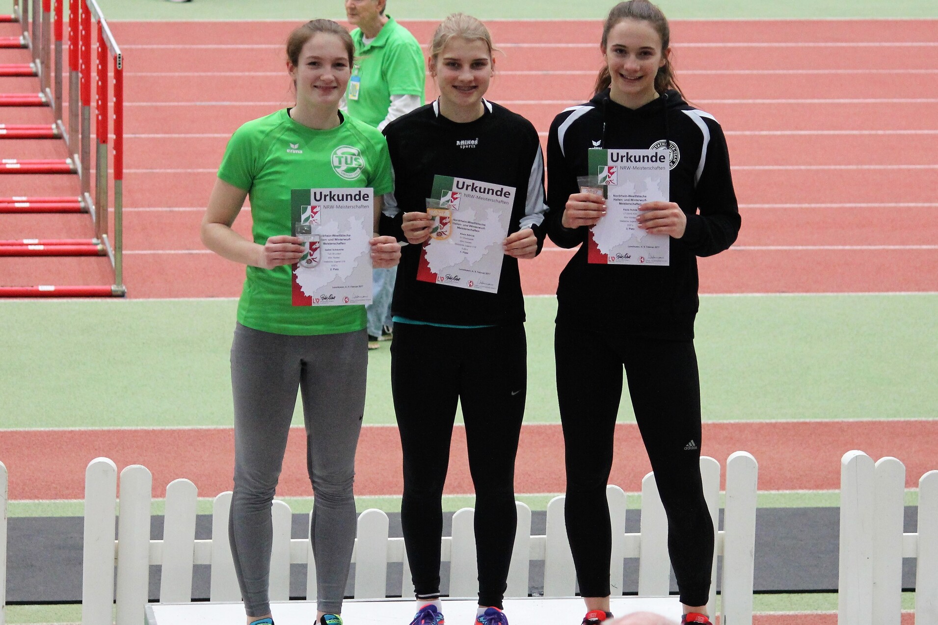 Drei Medaillengewinnerinnen stehen auf dem Siegertreppchen und halten Urkunden in den H&auml;nden.