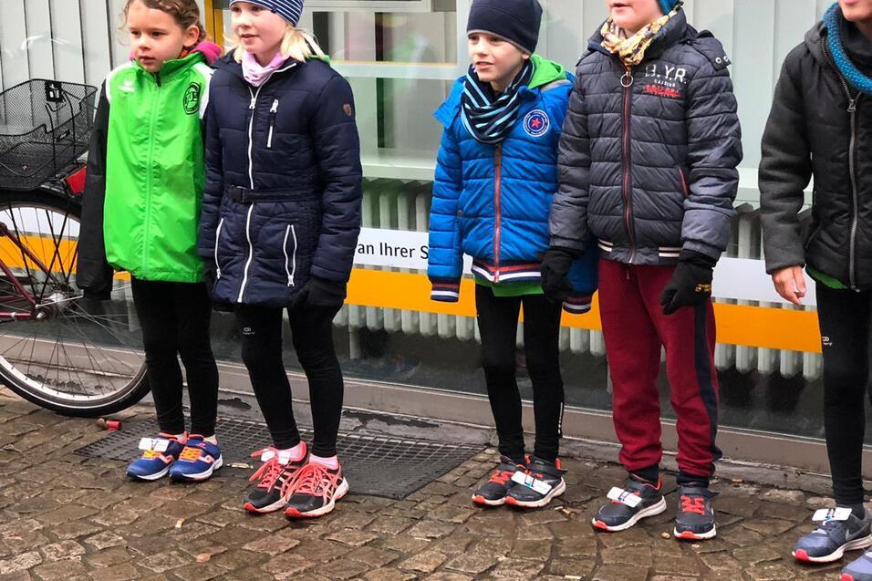 F&uuml;nf Kinder in Sportkleidung stehen an einer Steintreppe, ein Fahrrad ist im Hintergrund sichtbar.