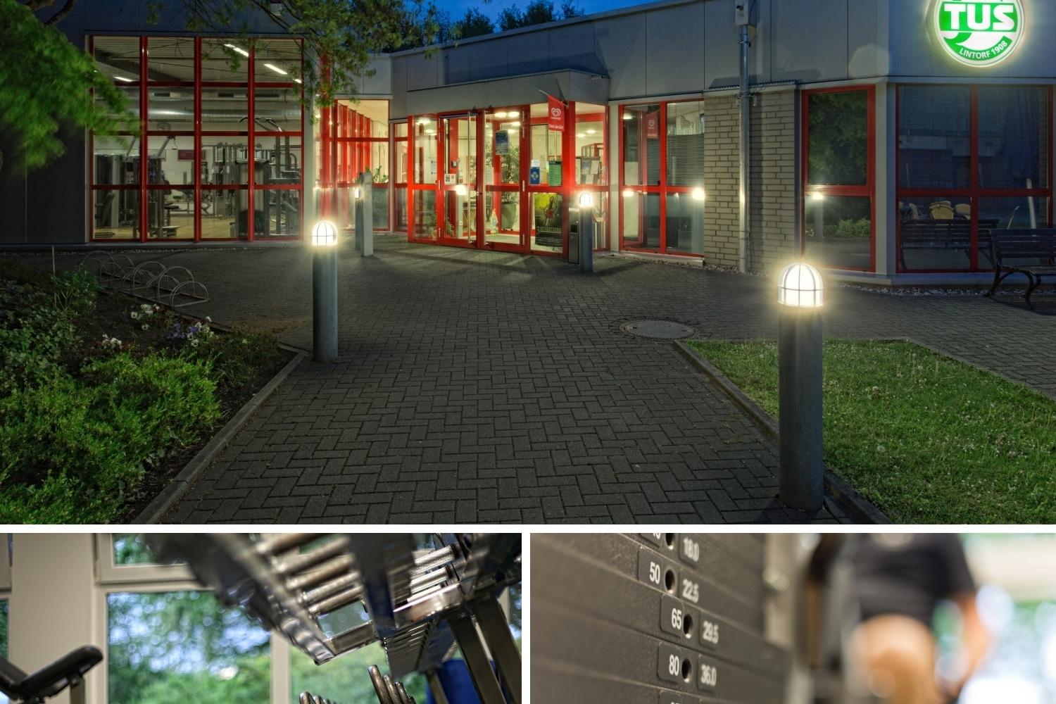 Eingang eines Fitnessstudios bei Dämmerung mit beleuchtetem Logo und Umgebungsbeleuchtung, darunter Fitnessgeräte und Gewichte.
