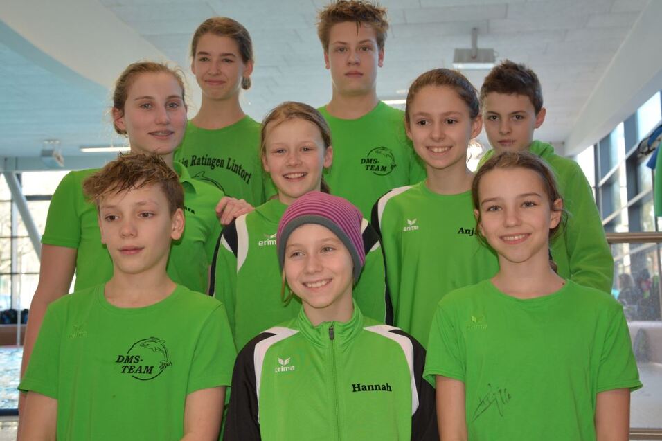 Gruppenfoto von neun Schwimmern in gr&uuml;nen Trikots am Schwimmbecken, l&auml;chelnd und in zwei Reihen angeordnet.