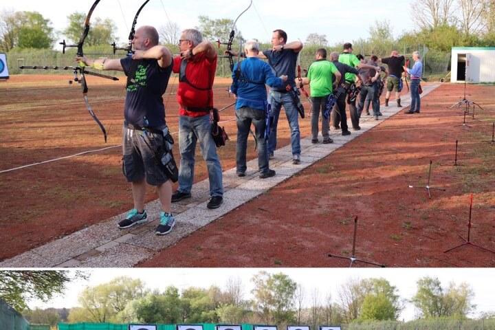 Gruppe von Bogensch&uuml;tzen in Reihe, die auf Zielscheiben in der Ferne zielen, auf einem Au&szlig;enplatz.