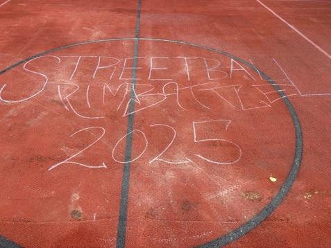 Kreidezeichnung &bdquo;STREETBALL RIM BATTLE 2025&ldquo; auf dem roten Sportplatz.