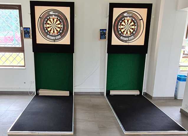 Zwei Dartscheiben mit elektronischen Anzeigetafeln an einer Wand in einem hellen Raum.