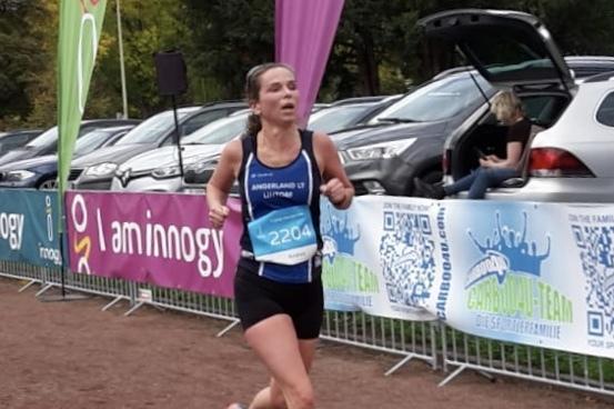 L&auml;uferin mit Startnummer 2204 sprintet auf einer Laufstrecke, umgeben von Zuschauern und Werbebannern.