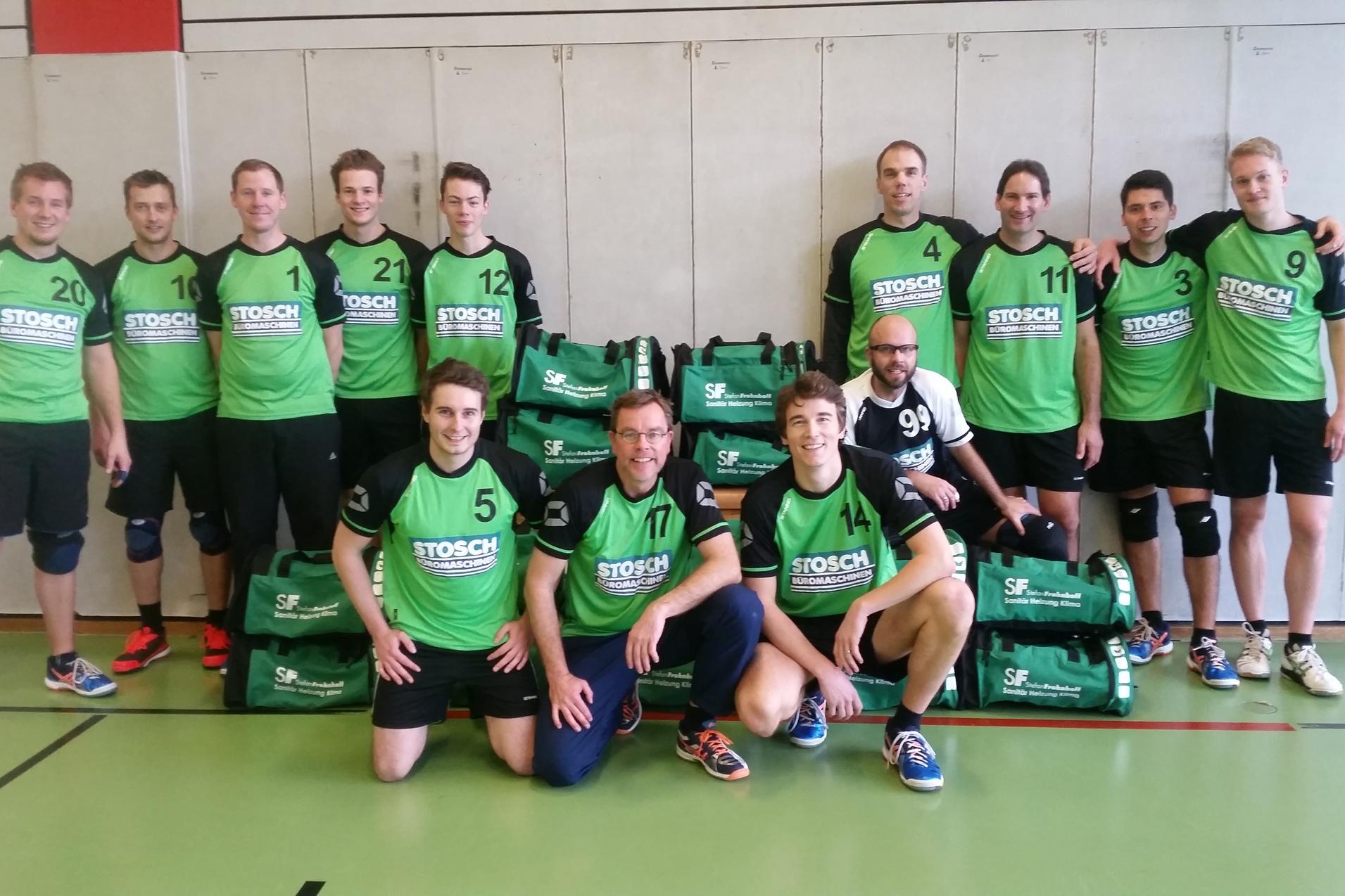 Mannschaftsaufstellung von zwölf Sportlern in grünen Trikots vor stapelbaren Sporttaschen auf einem Hallenboden.