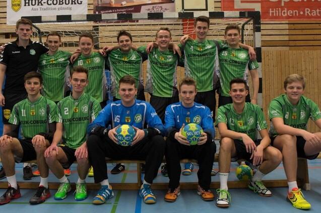 Teambild einer m&auml;nnlichen Handballmannschaft in gr&uuml;nen Trikots, aufgestellt und sitzend in einer Sporthalle.