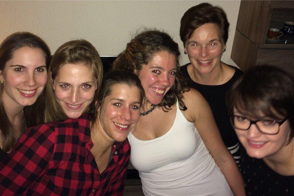 Sechs Frauen stehen l&auml;chelnd nahe beieinander, vor einer hellen Wand, in einem gem&uuml;tlichen Raum.