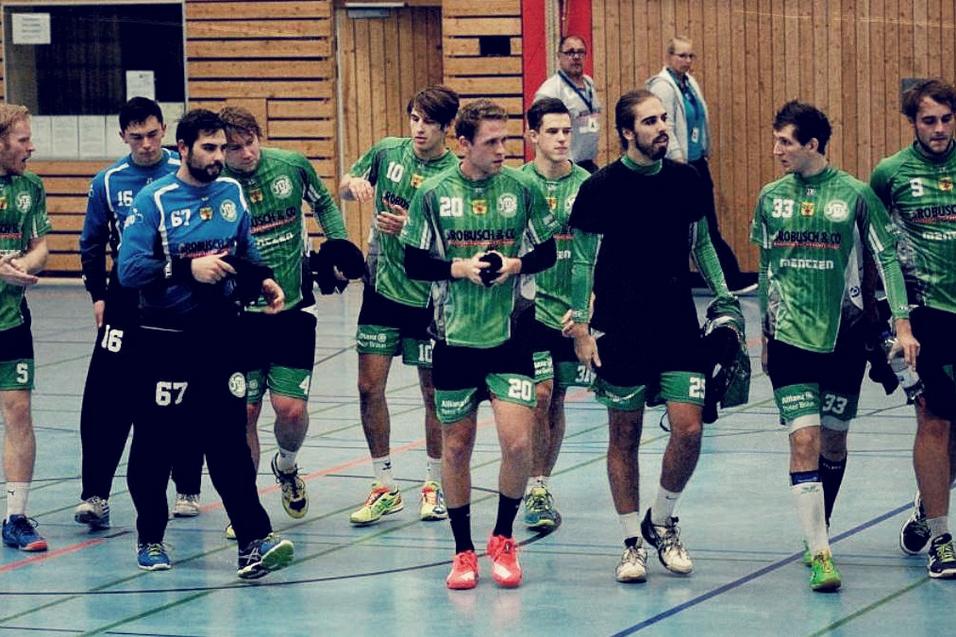 Handballmannschaft in gr&uuml;nen Trikots verl&auml;sst das Spielfeld, w&auml;hrend sie sich unterhalten und ihre Ausr&uuml;stung tragen.