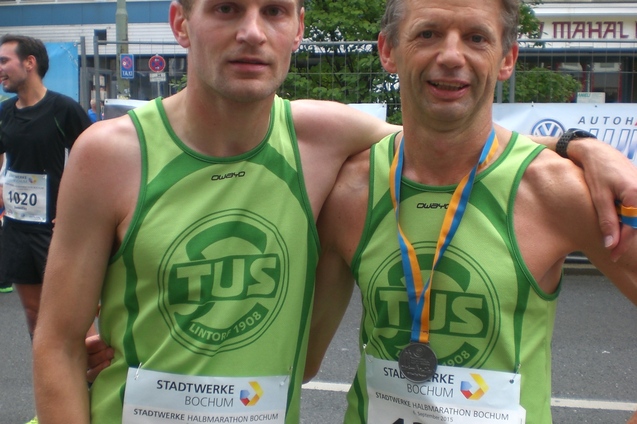 Zwei L&auml;ufer in gr&uuml;nen Trikots mit Medaille um den Hals posieren nach einem Wettkampf in Bochum.