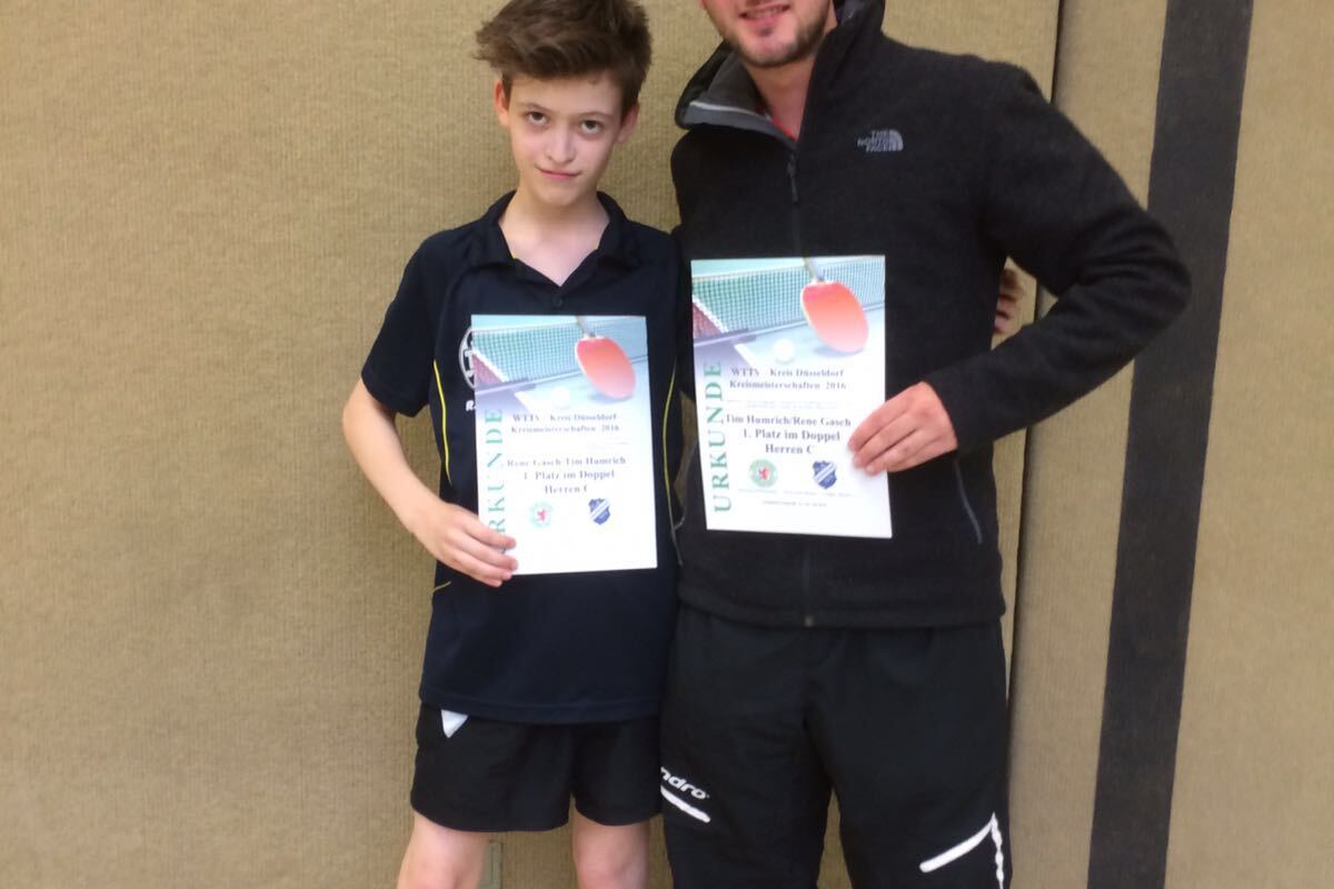 Zwei junge M&auml;nner stehen nebeneinander und halten jeweils eine Urkunde in der Hand, vor einer Wand in einer Sporthalle.