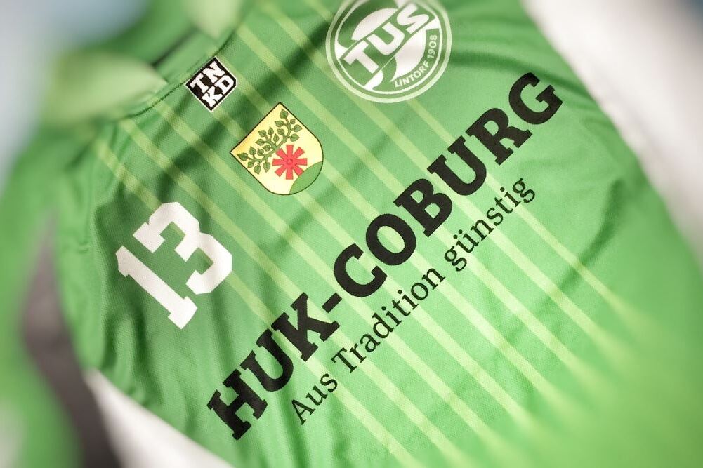 Gr&uuml;ne Sporttrikots mit der Nummer 13, dem Schriftzug &bdquo;HUK-COBURG&ldquo; und einem Vereinslogo.