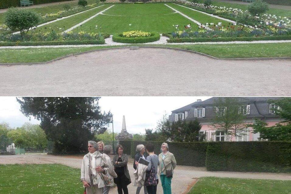 Gruppe von Menschen in einem Park mit Blumenbeeten und verwinkelten Wegen, im Hintergrund eine historische Geb&auml;udeansicht.