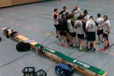 Eine Gruppe von Spielern versammelt sich in einem Sportgymnasium zu einer Besprechung, B&auml;nke und Sporttaschen im Hintergrund.