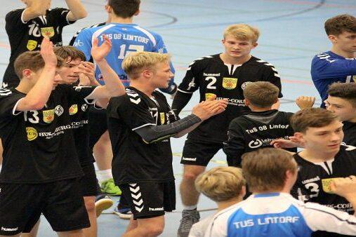 Handballspieler in schwarz und blau applaudieren und feiern nach einem Spiel in einer Sporthalle.
