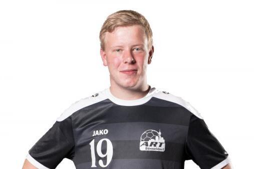 Ein junger Mann in einem schwarz-wei&szlig;en Fu&szlig;balltrikot mit der Nummer 19 steht mit verschr&auml;nkten Armen vor einem wei&szlig;en Hintergrund.