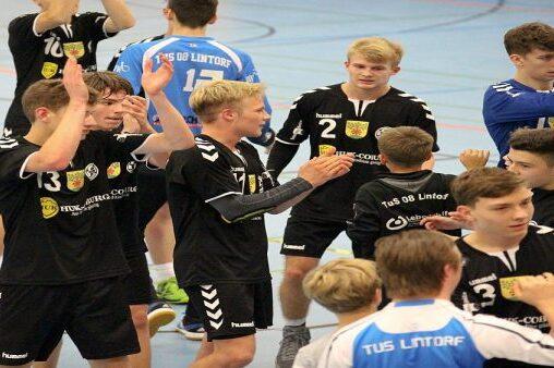 Handballspieler in schwarz und blau applaudieren und feiern nach einem Spiel in einer Sporthalle.