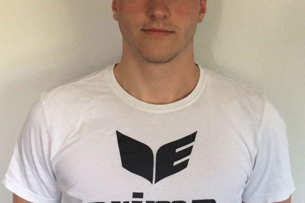 Junger Mann mit Kappe und T-Shirt mit dem Aufdruck &bdquo;erima&ldquo; vor einem wei&szlig;en Hintergrund.